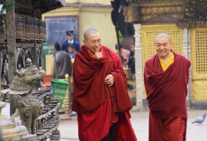 Buddhist Monks strolling around the stupa's prayer wheels