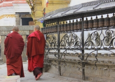 Buddhist Monks strolling around the stupa's prayer wheels